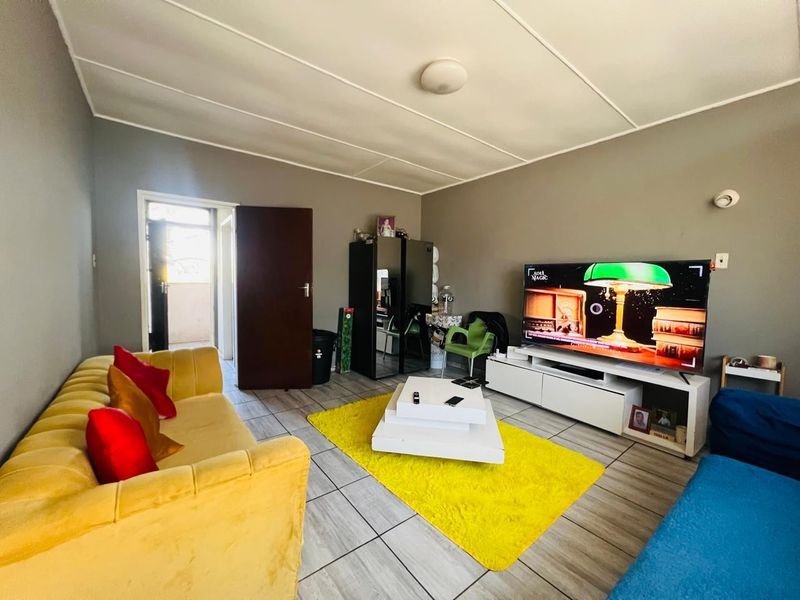 A living room featuring tiled flooring and a panelled ceiling, providing a functional and comfortable space for relaxation.