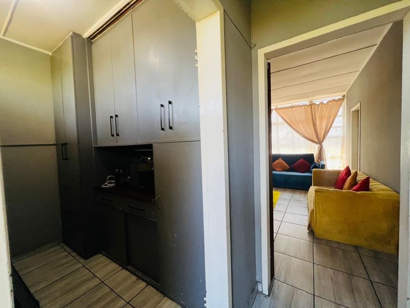 A functional kitchen area featuring built-in cabinetry and tiled flooring, with a direct view into the adjacent living space.