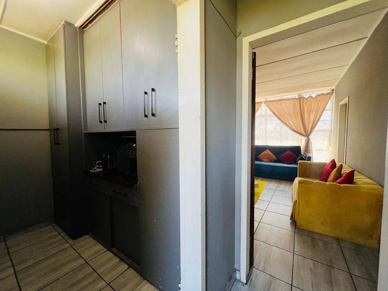 Open plan living area featuring tiled flooring and built-in cabinetry, providing a functional transition between the kitchen and living space.