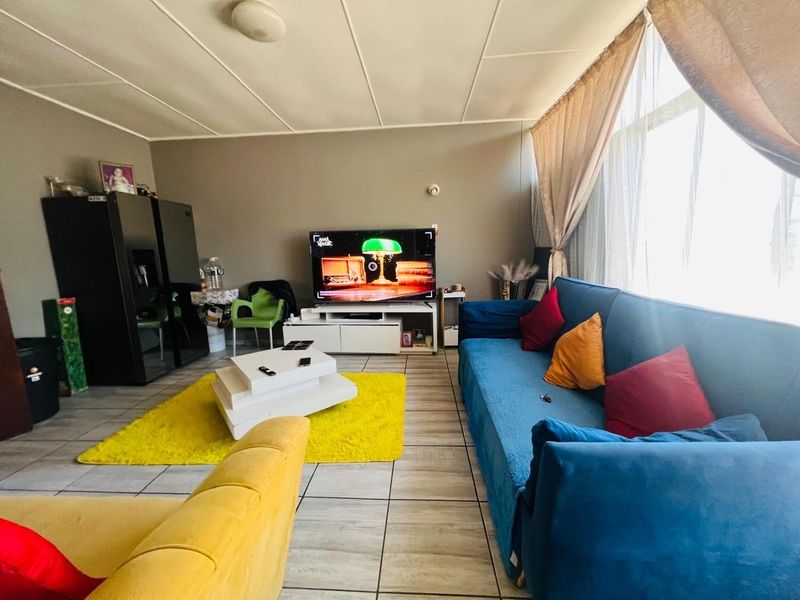 A living room featuring tiled flooring and a large window, providing a functional space with potential for modern updates.