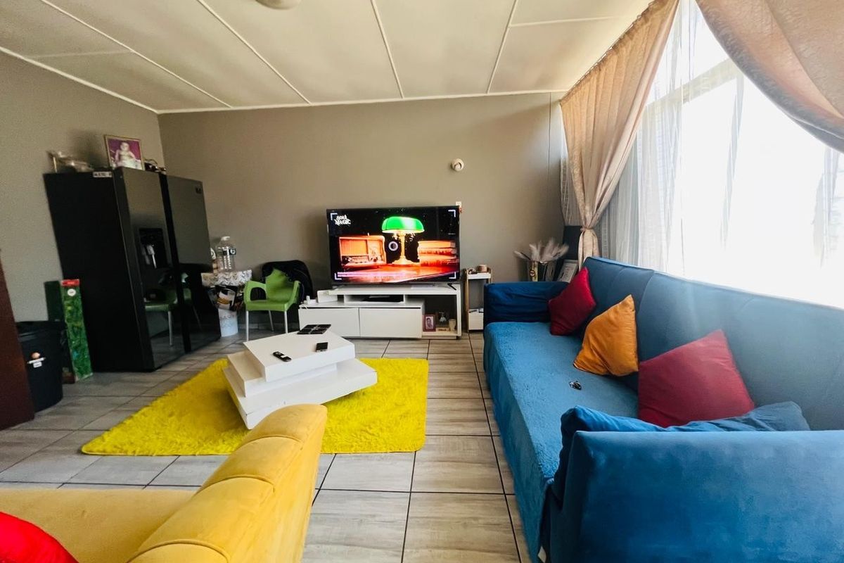 A living room featuring tiled flooring and a large window, providing a functional space with potential for modern updates.