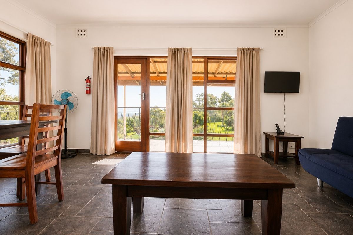 A bright living area featuring tiled floors and large glass sliding doors that provide access to an outdoor patio with scenic views.