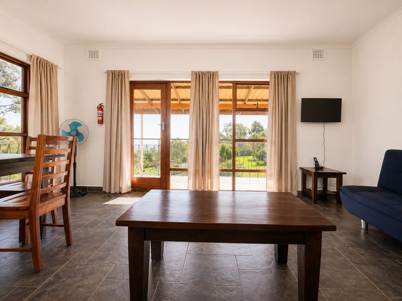 A bright living area featuring tiled floors and large glass sliding doors that provide access to an outdoor patio with scenic views.