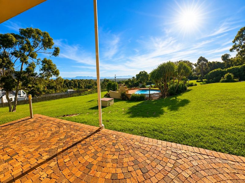 Spacious rear garden featuring a brick-paved patio, a swimming pool with fencing, and expansive lawn areas with scenic landscape views.