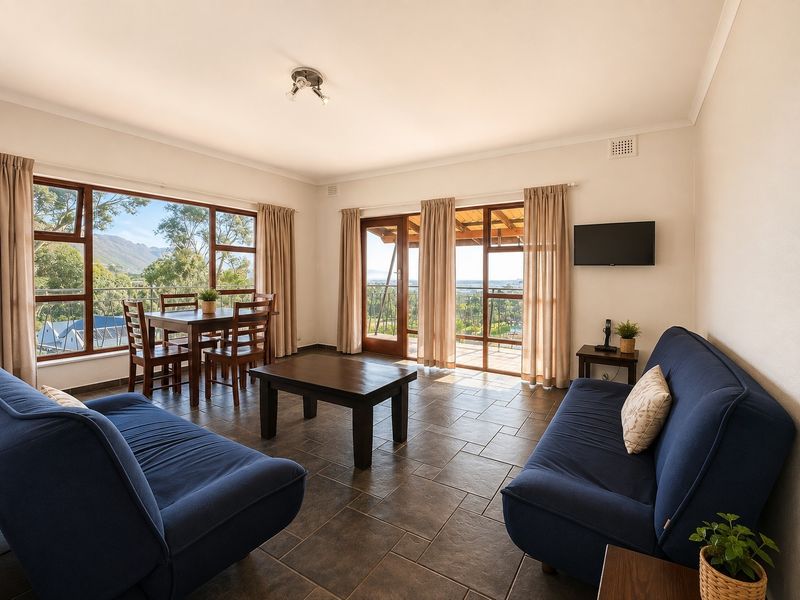 Spacious open-plan living and dining area featuring tiled floors, large windows, and glass doors leading to an outdoor patio with scenic views.