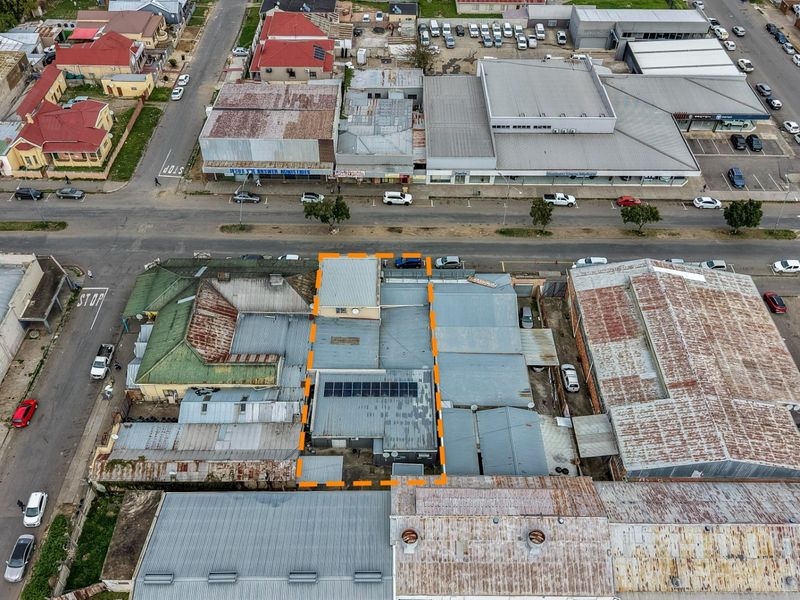Aerial view of a commercial property featuring a metal roof with installed solar panels, situated in a dense urban business district.