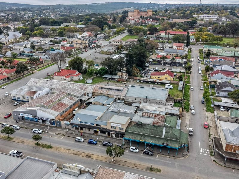 Aerial view of a commercial block featuring multiple storefronts with corrugated metal roofing, situated in a busy urban street setting.