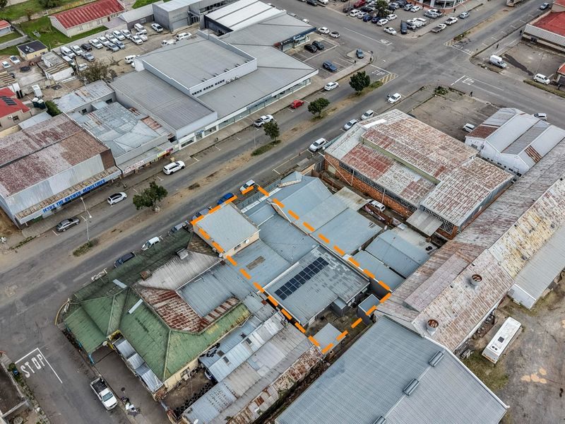 Aerial view of the property highlighting the roof structure, including corrugated metal roofing and installed solar panels within an urban business district.