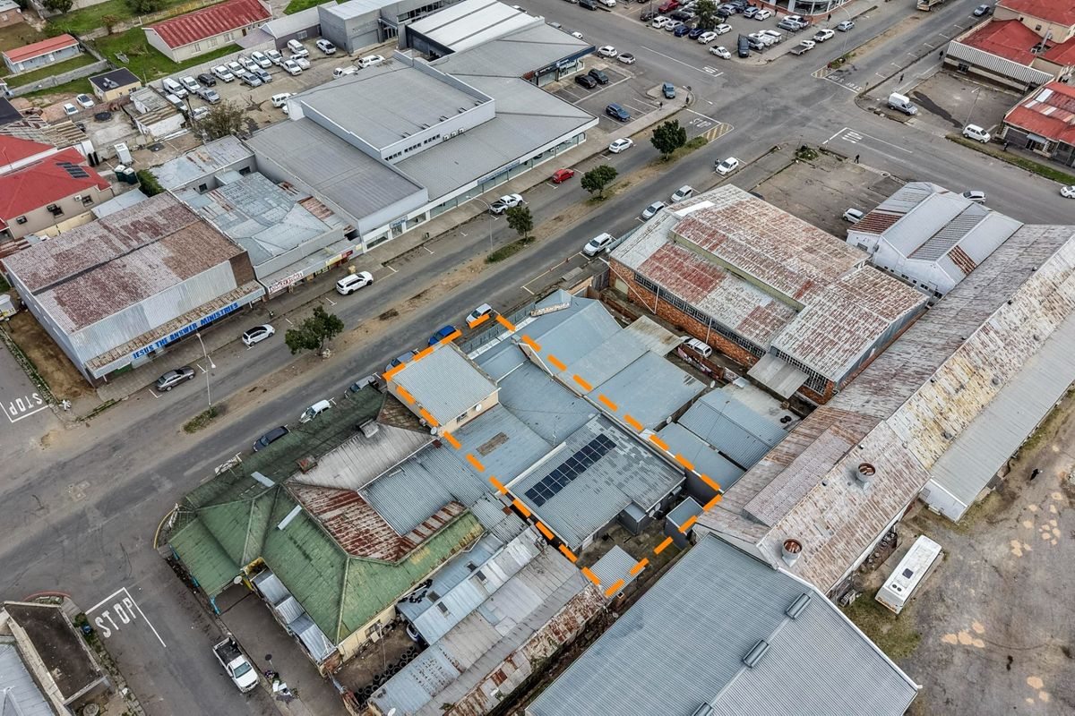 Aerial view of the property highlighting the roof structure, including corrugated metal roofing and installed solar panels within an urban business district.