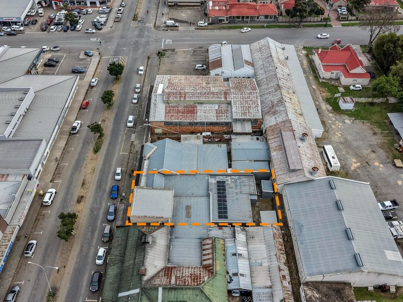 Aerial view of a commercial property complex featuring multiple corrugated metal roof sections, integrated solar panels, and surrounding street access.