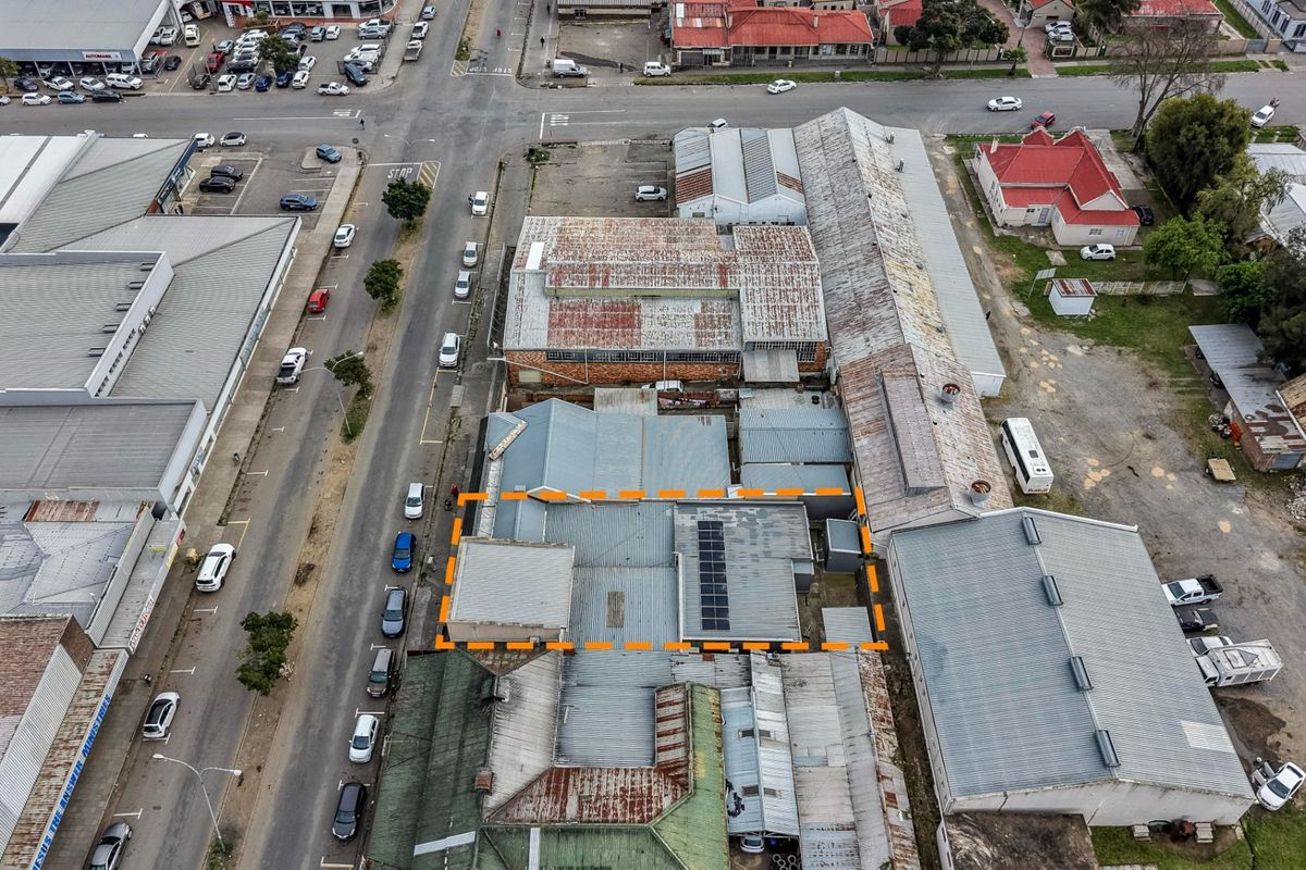 Aerial view of a commercial property complex featuring multiple corrugated metal roof sections, integrated solar panels, and surrounding street access.