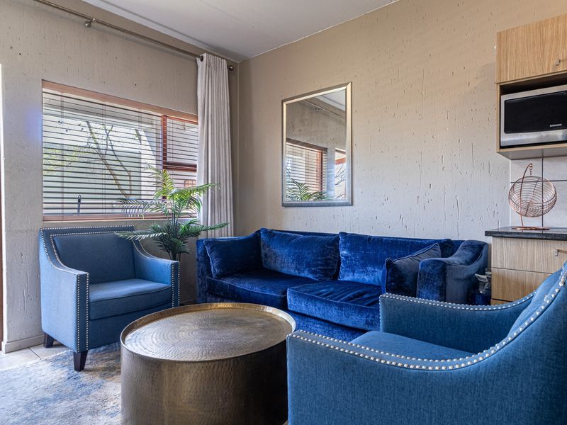 A comfortable living area featuring textured walls, tiled flooring, and a built-in microwave unit, with direct access to an outdoor balcony.