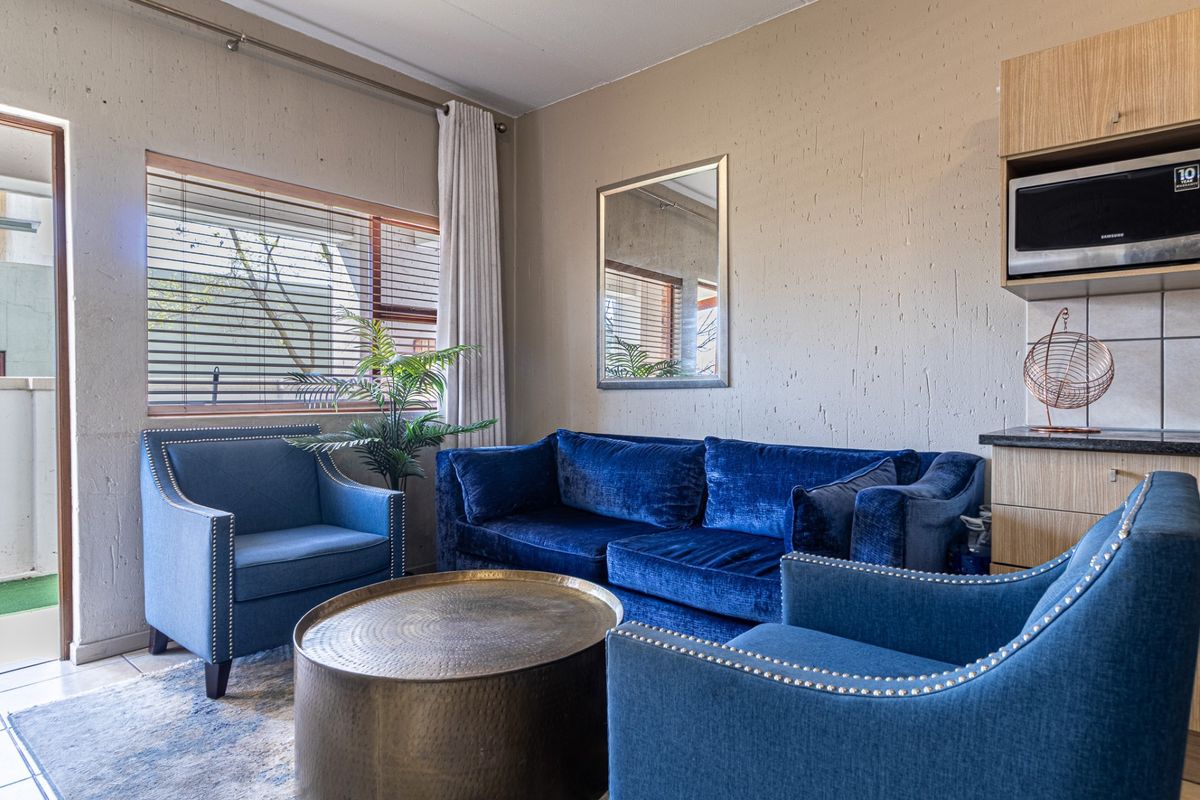 A comfortable living area featuring textured walls, tiled flooring, and a built-in microwave unit, with direct access to an outdoor balcony.