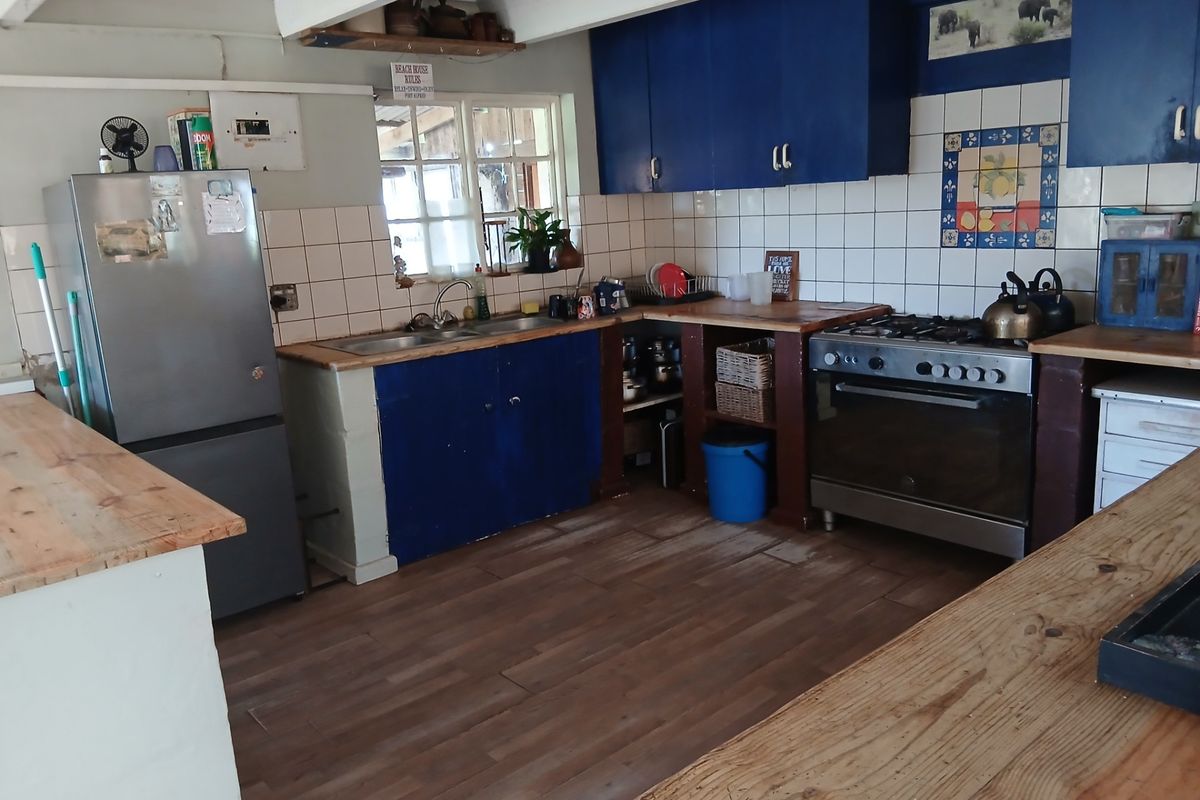 A functional kitchen featuring blue cabinetry, wooden countertops, a gas stove, and a tiled backsplash, offering a rustic aesthetic with potential for modernization.