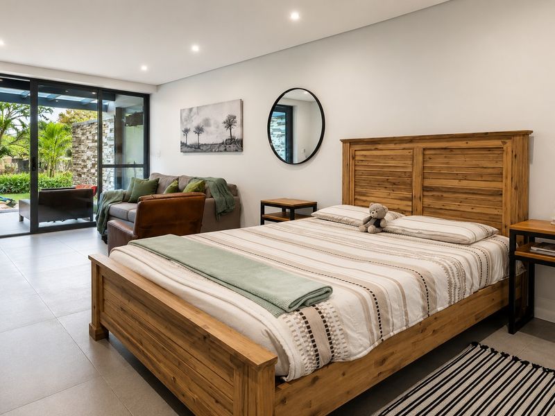 Spacious bedroom featuring modern tiled flooring, recessed lighting, and large sliding glass doors providing seamless access to the outdoor patio area.