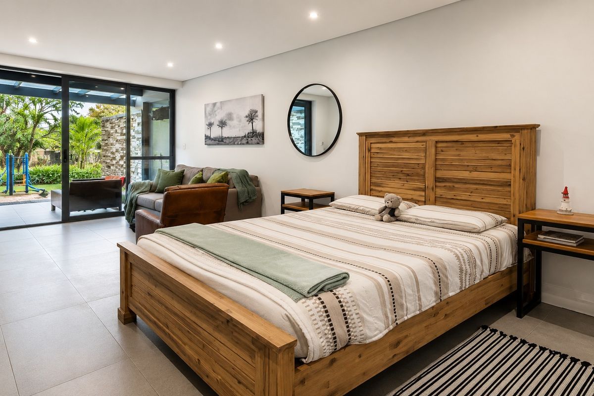 Spacious bedroom featuring modern tiled flooring, recessed lighting, and large sliding glass doors providing seamless access to the outdoor patio area.