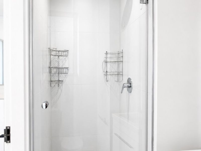 A clean, modern bathroom featuring a glass-enclosed shower with tiled flooring and contemporary fixtures.