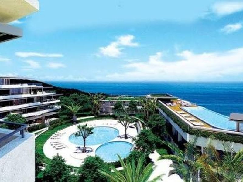 Aerial view of a modern residential complex featuring multiple swimming pools, landscaped gardens, and expansive ocean views.