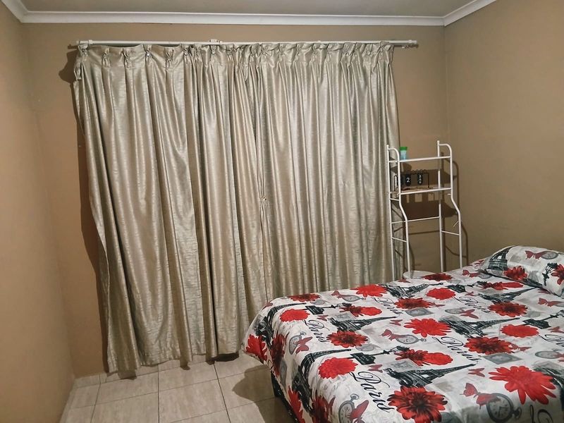 A bedroom featuring tiled flooring and neutral wall tones, providing a functional space ready for personalization.