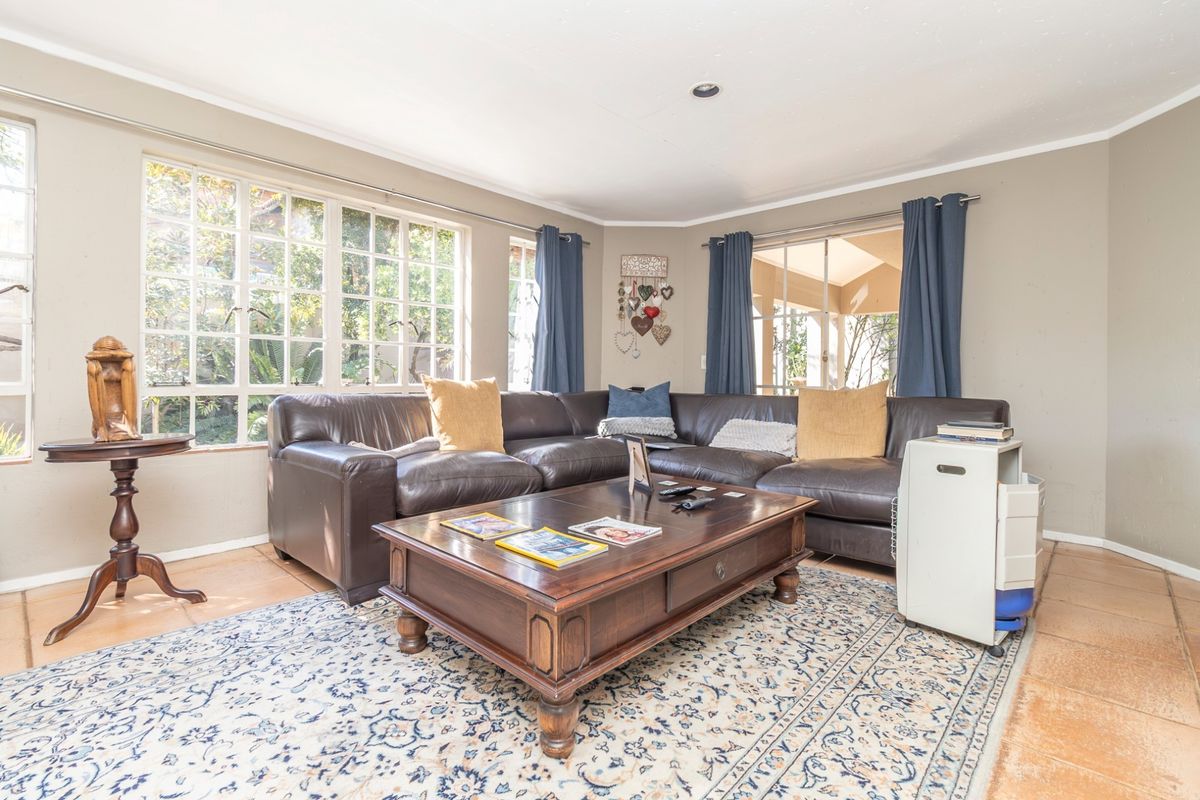 A comfortable living room featuring tiled flooring, recessed lighting, and large windows that provide ample natural light and access to the outdoor area.