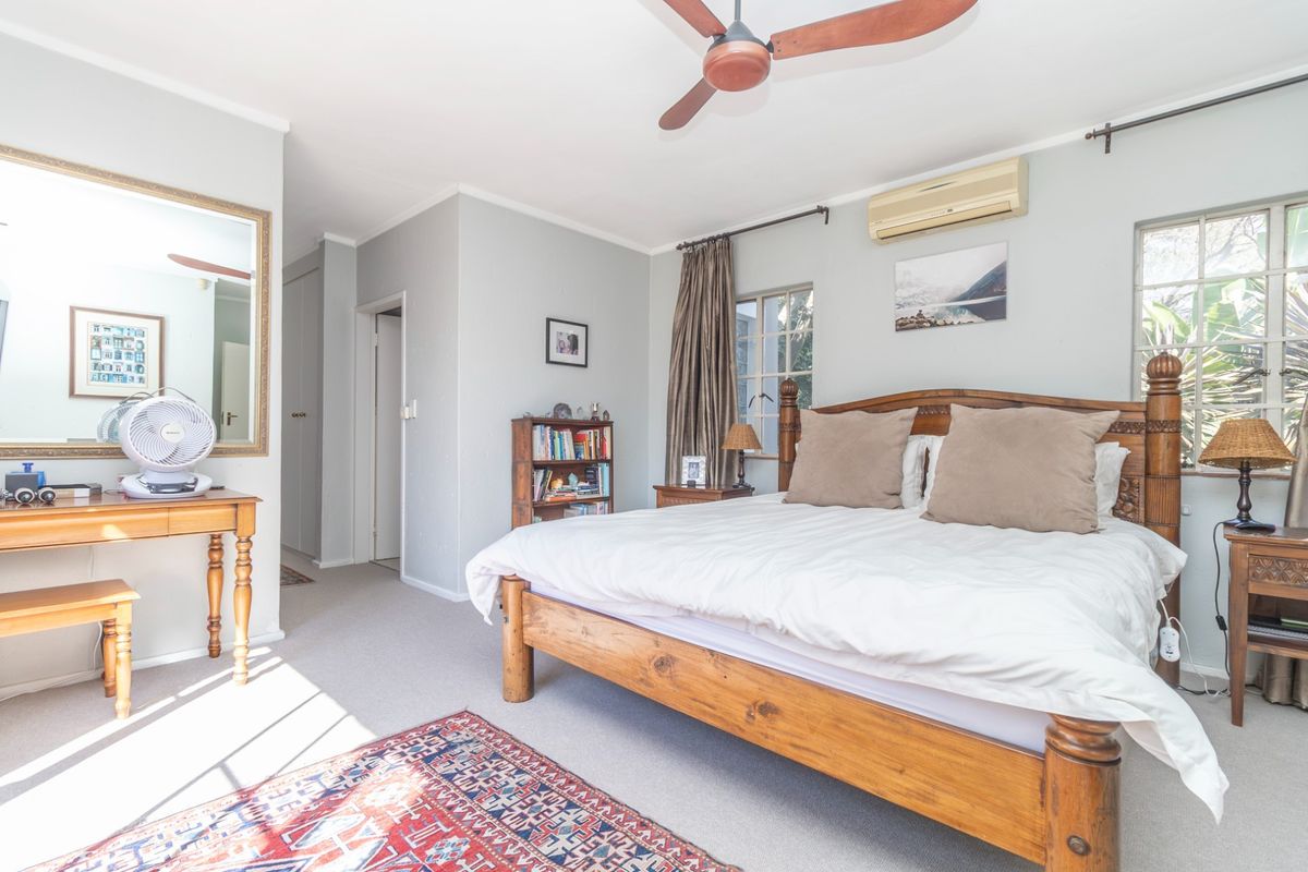 A spacious bedroom featuring a ceiling fan, split-system air conditioning, and large windows that provide natural light.