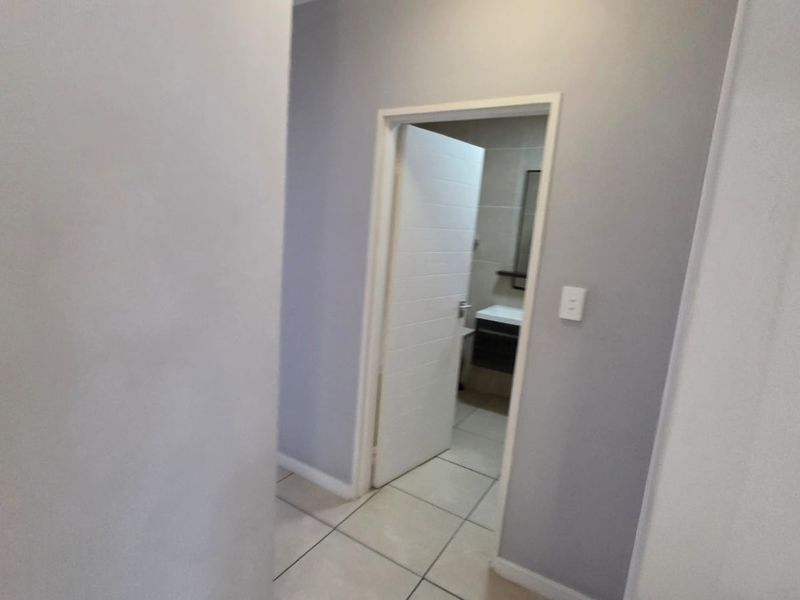 A view through a hallway leading into a bathroom with tiled flooring and neutral wall finishes.