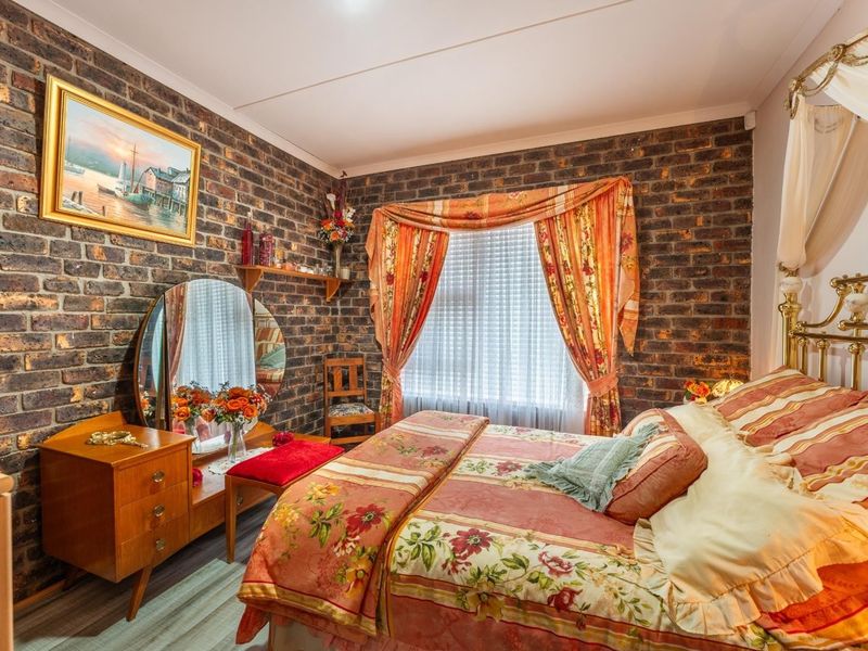 A bedroom featuring a prominent exposed brick feature wall and a window with curtains.