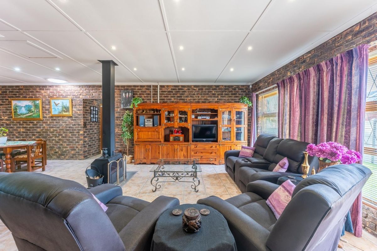 Spacious living room featuring exposed brick walls, tiled flooring, and a central freestanding fireplace, creating a warm and rustic atmosphere.