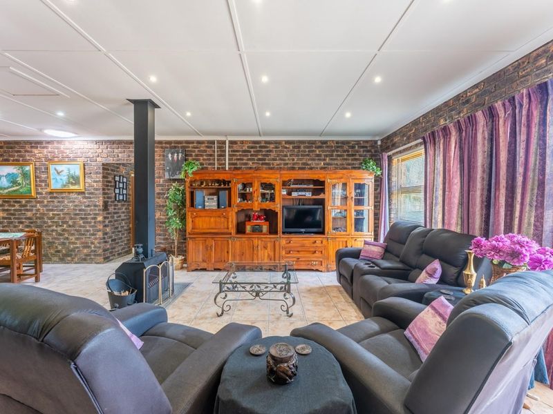 Spacious living room featuring exposed brick walls, tiled flooring, and a central freestanding fireplace, creating a warm and rustic atmosphere.