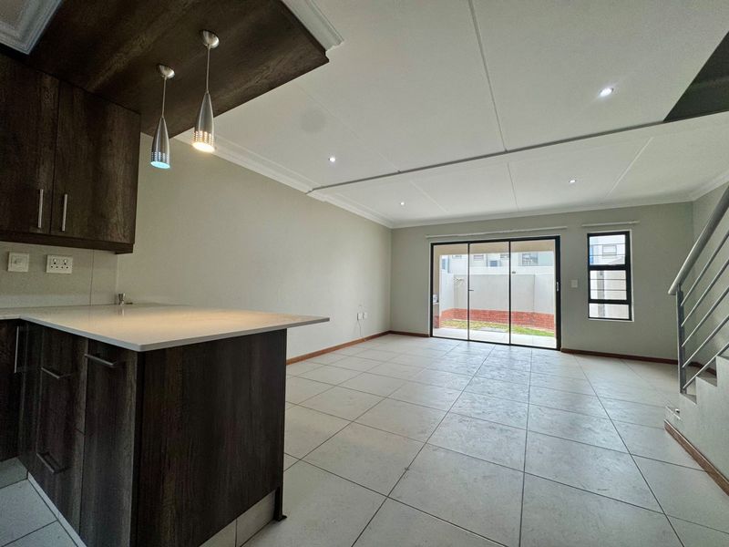 Spacious open-plan living and kitchen area featuring modern dark cabinetry, tiled floors, recessed lighting, and sliding doors leading to a private outdoor space.
