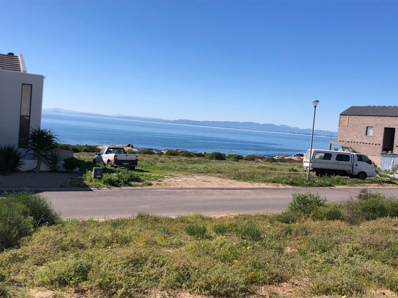 A scenic view of the ocean and distant mountains from a vacant residential plot.