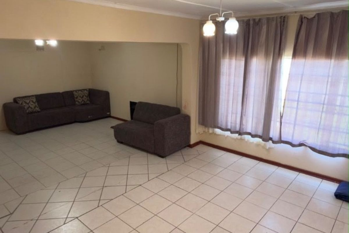 Spacious living area featuring tiled flooring and large windows with curtain rails, offering a blank canvas for potential interior updates.