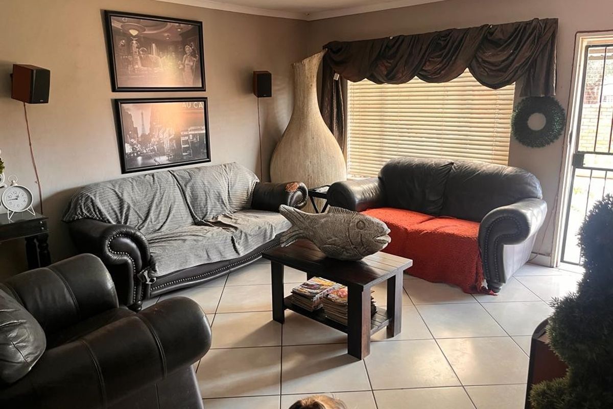 A living room featuring tiled flooring, a security gate entrance, and venetian blinds, providing a functional and lived-in space.