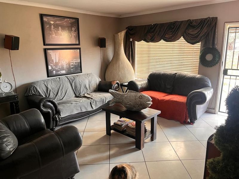 A living room featuring tiled flooring, a security gate entrance, and venetian blinds, providing a functional and lived-in space.