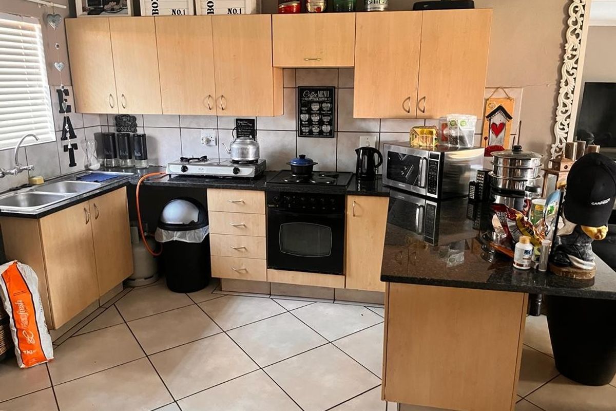 Functional kitchen featuring light wood cabinetry, granite countertops, built-in oven, electric hob, and tiled flooring with a practical layout.
