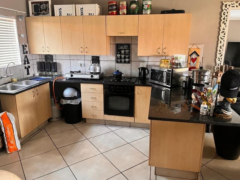 Functional kitchen featuring light wood cabinetry, granite countertops, built-in oven, electric hob, and tiled flooring with a practical layout.
