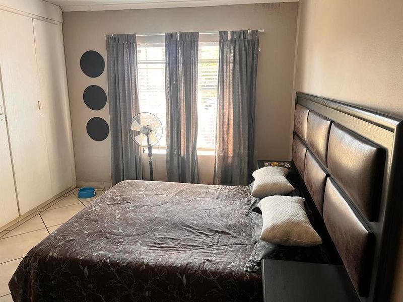 A bedroom featuring built-in cupboards and tiled flooring, offering a functional space with potential for cosmetic updates.
