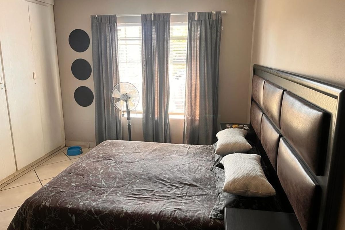 A bedroom featuring built-in cupboards and tiled flooring, offering a functional space with potential for cosmetic updates.