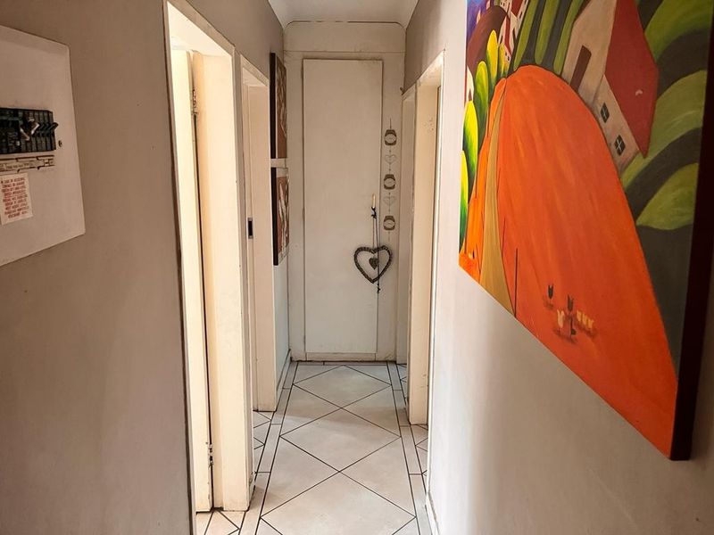 A functional apartment hallway featuring tiled flooring and a wall-mounted electrical distribution board, providing access to multiple rooms.