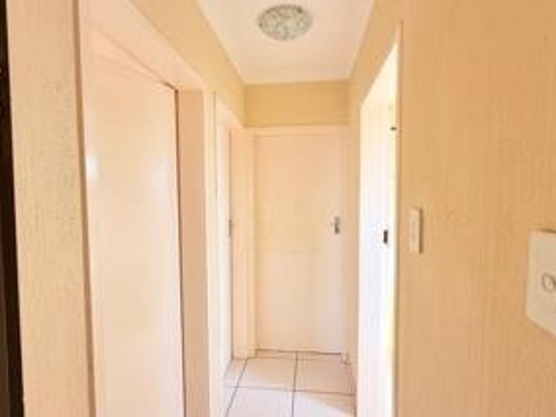 A clean and functional hallway featuring tiled flooring, neutral wall finishes, and multiple internal doors providing access to various rooms.