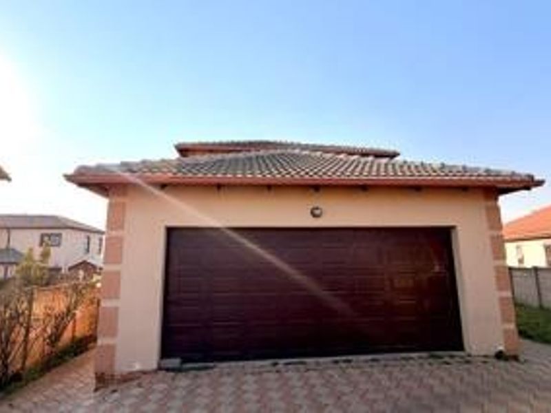 A detached garage featuring a tiled roof and a dark sectional door, situated on a paved driveway.