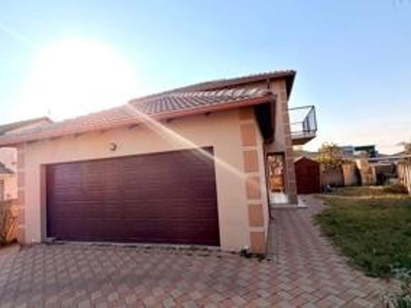 Front view of a residential property featuring a double garage, paved driveway, and an upper-level balcony.