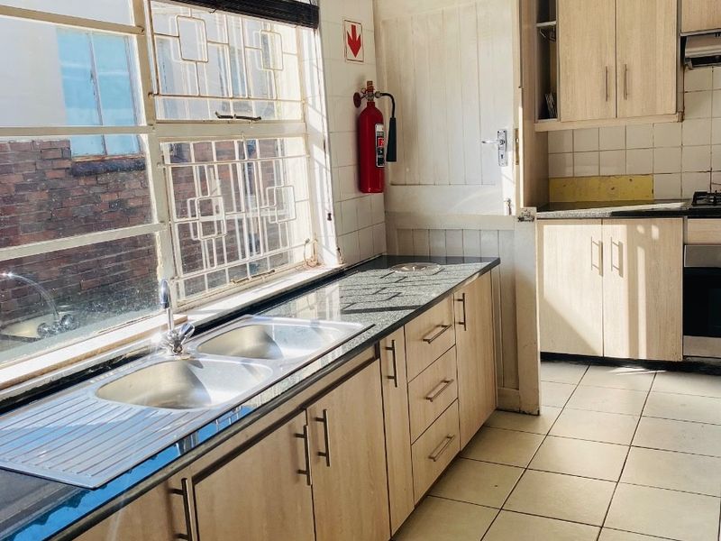 A functional kitchen featuring granite countertops, double sink, built-in cabinetry, and ceramic floor tiles, offering a clean and practical workspace.