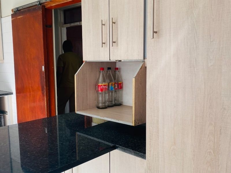 Kitchen area featuring light wood-look cabinetry, dark granite countertops, and tiled flooring, with an adjacent sliding door entrance.