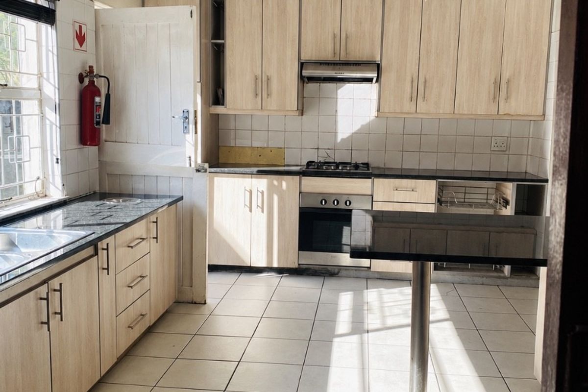 A functional kitchen featuring light wood cabinetry, granite countertops, a gas hob, and tiled flooring, offering a clean space ready for modern updates.