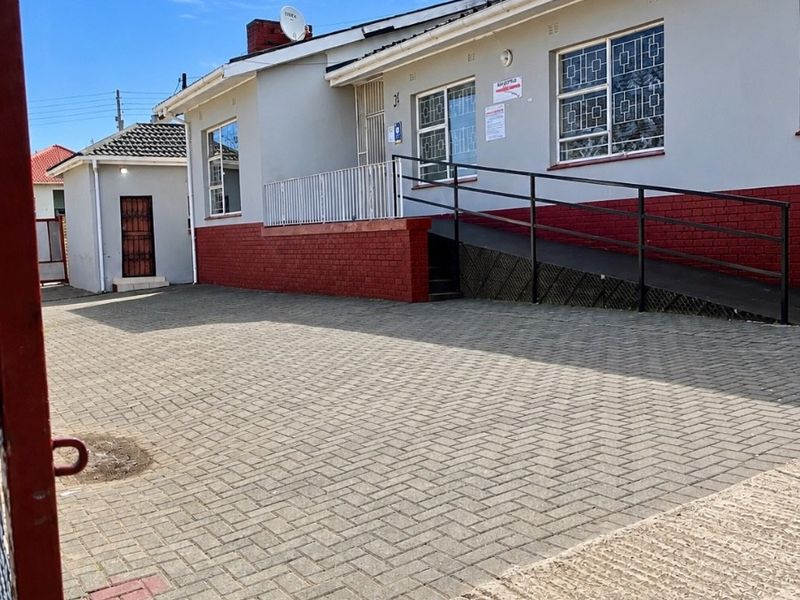 Front exterior view of the property featuring a paved driveway, wheelchair access ramp with metal handrails, and security bars on windows.