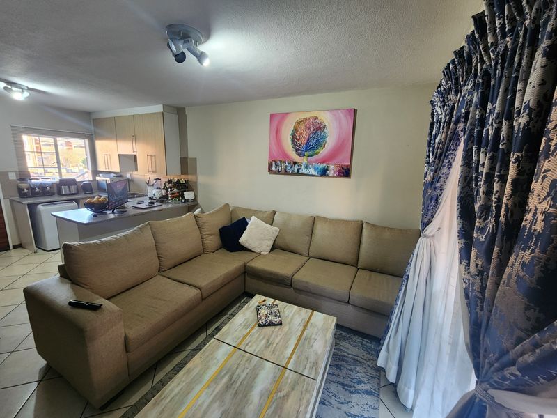 Open plan living area featuring a kitchen with island and tiled flooring, seamlessly connecting to the lounge space.