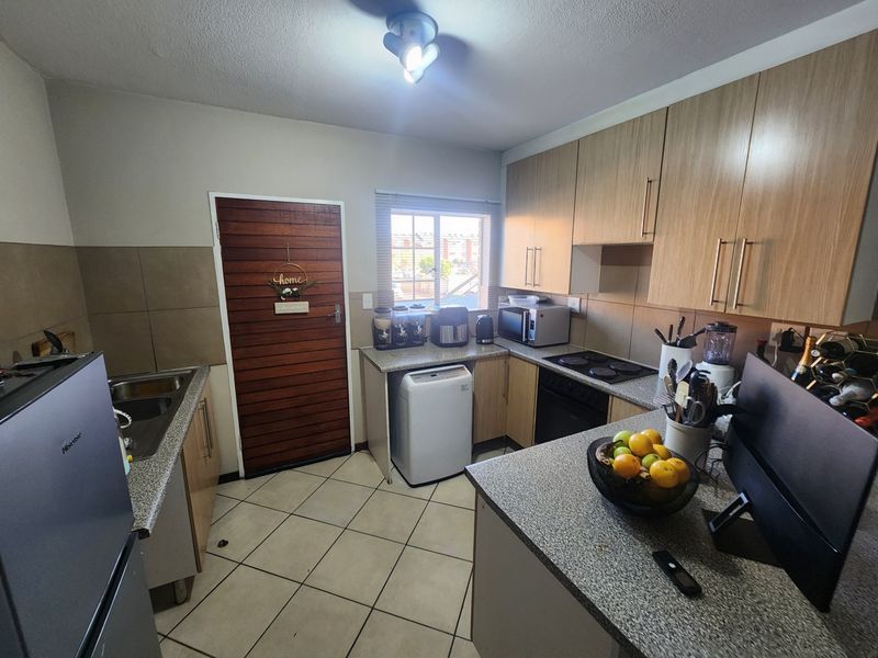 Functional kitchen featuring light wood-finish cabinetry, granite-look laminate countertops, tiled flooring, and integrated cooking appliances.