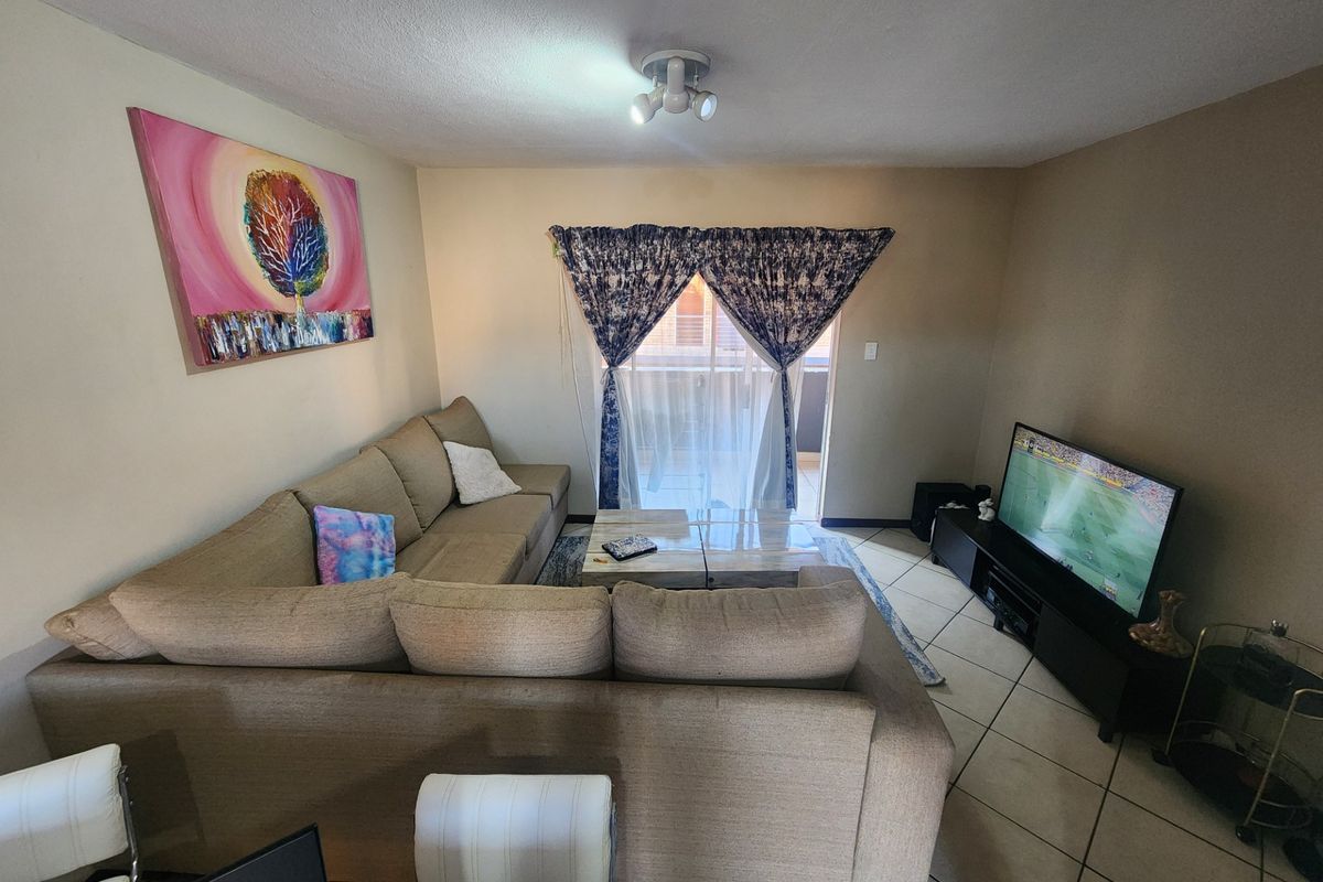 A functional living room featuring tiled flooring and a sliding glass door providing access to an outdoor area.