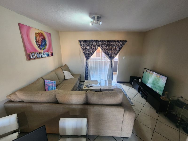 A functional living room featuring tiled flooring and a sliding glass door providing access to an outdoor area.